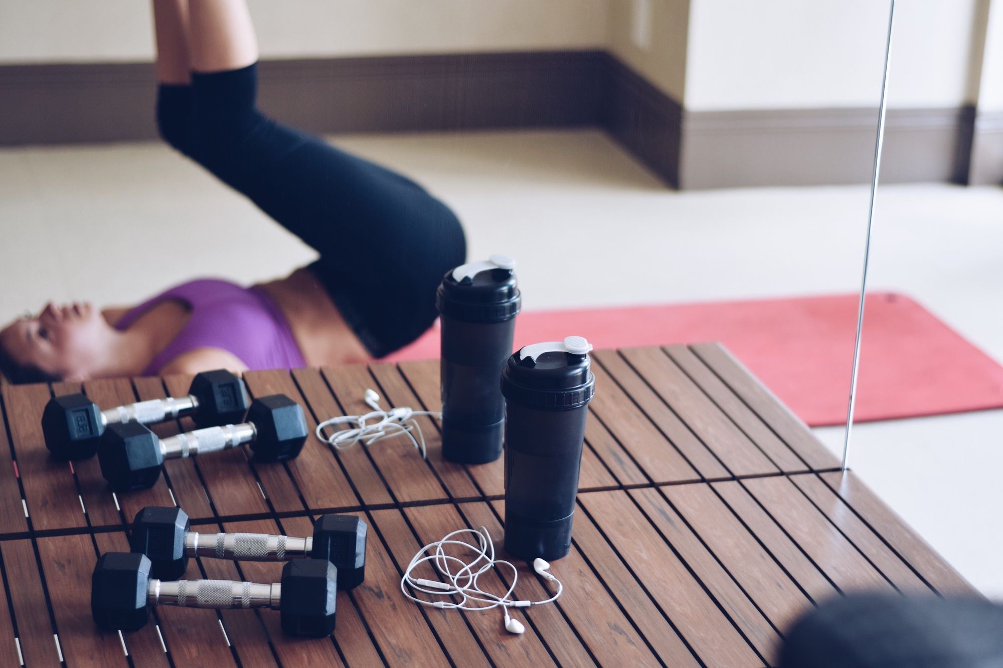 A reflection in a mirror of a girl working out on a yoga mat at the gym with her water bottle