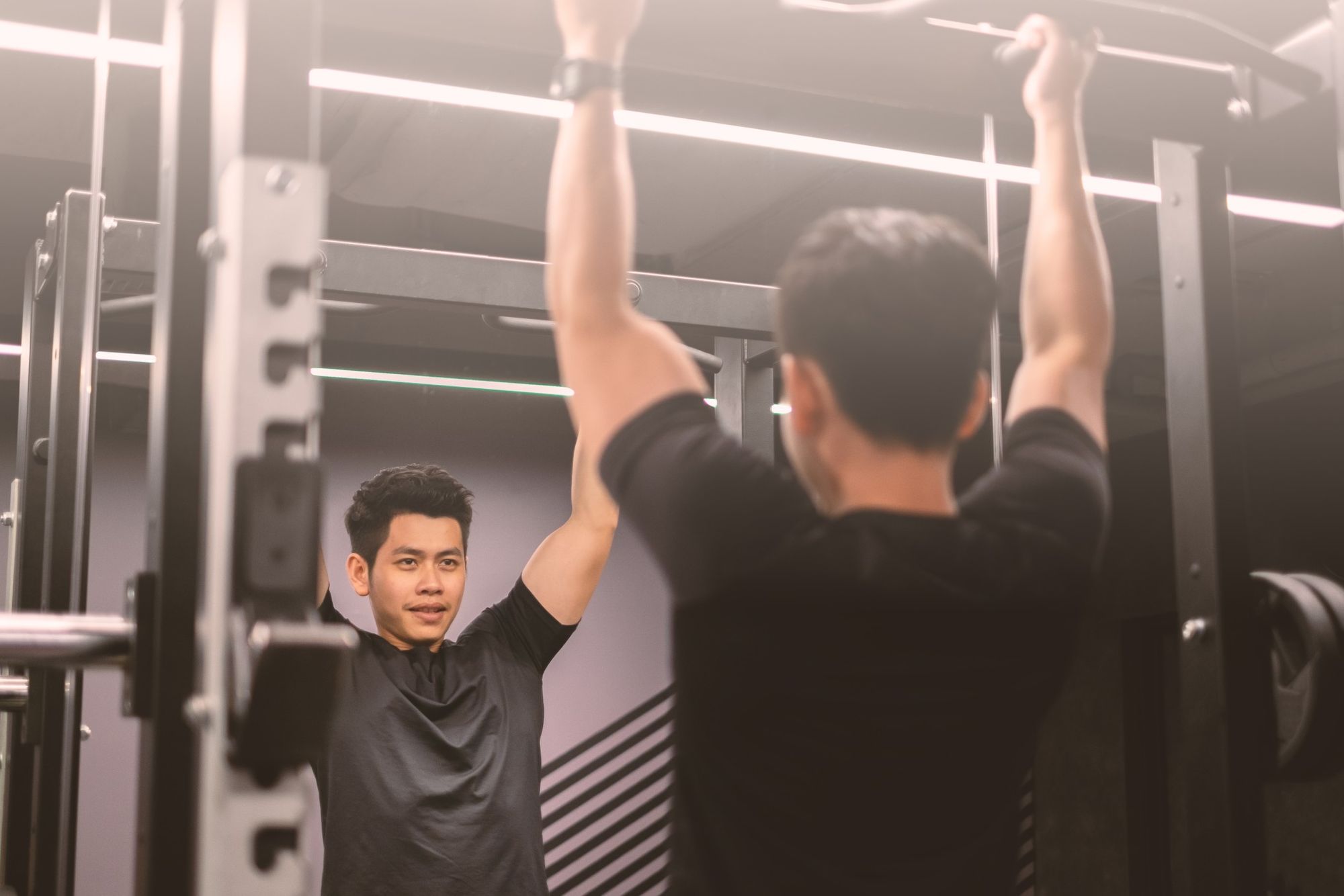 upper section portrait of an asian handsome and healthy man doing strength training in a gym he is