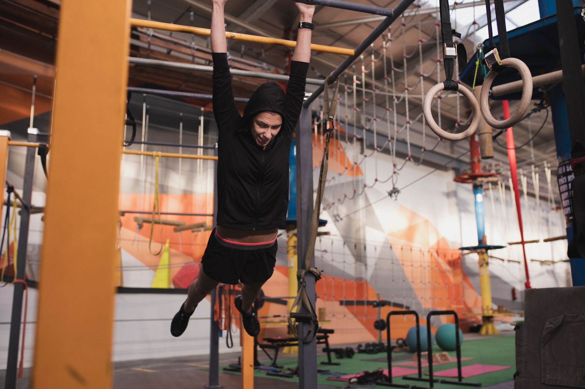 Young slim sportive lady in sportswear doing pull up exercises on horizontal bar in gym