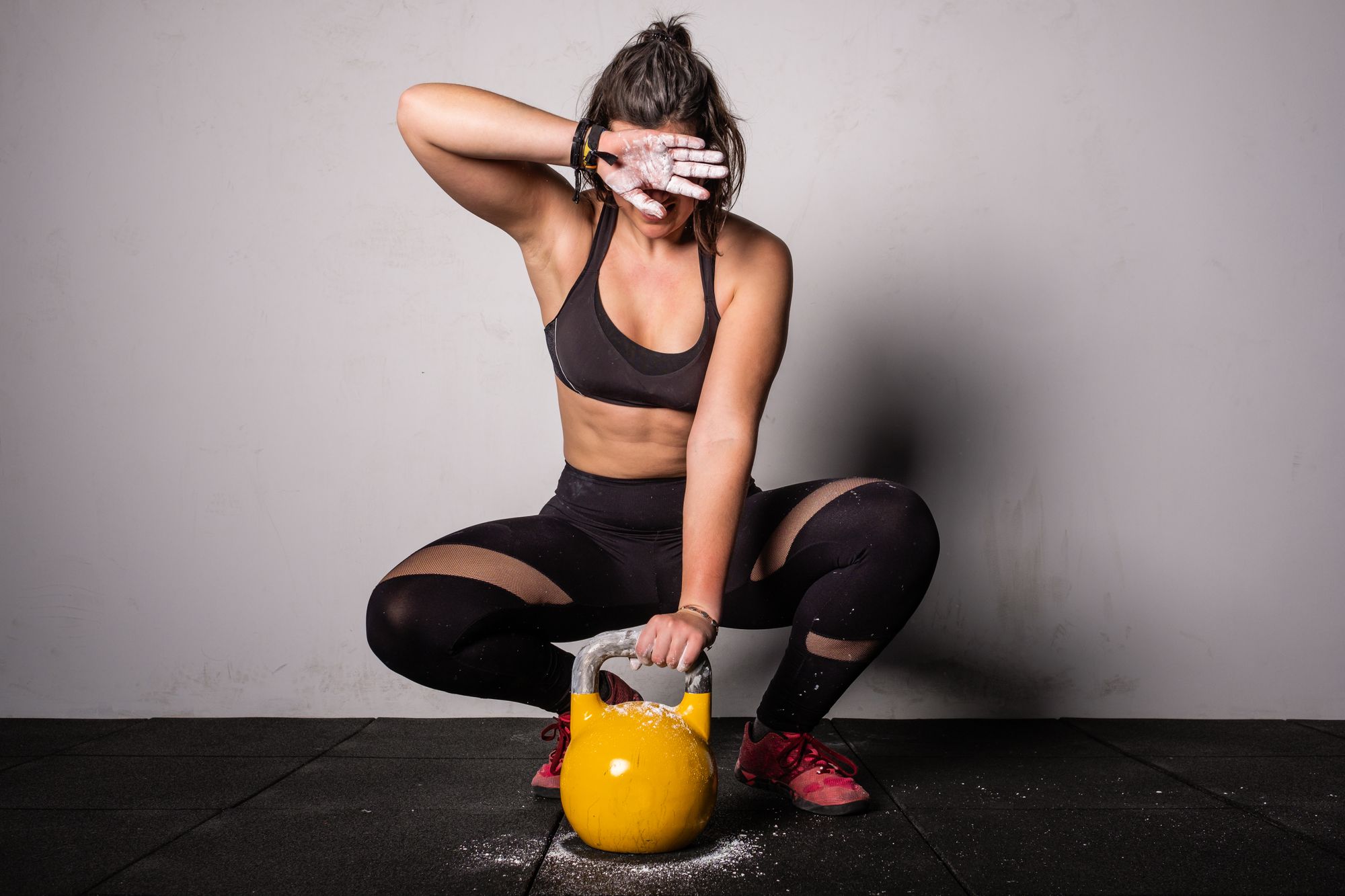 Athletic young concentrated woman in sportswear upping kettlebell in gym