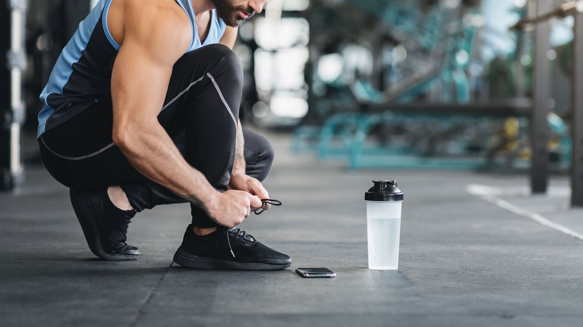 Athlete tying shoelaces before starting a workout in the gym