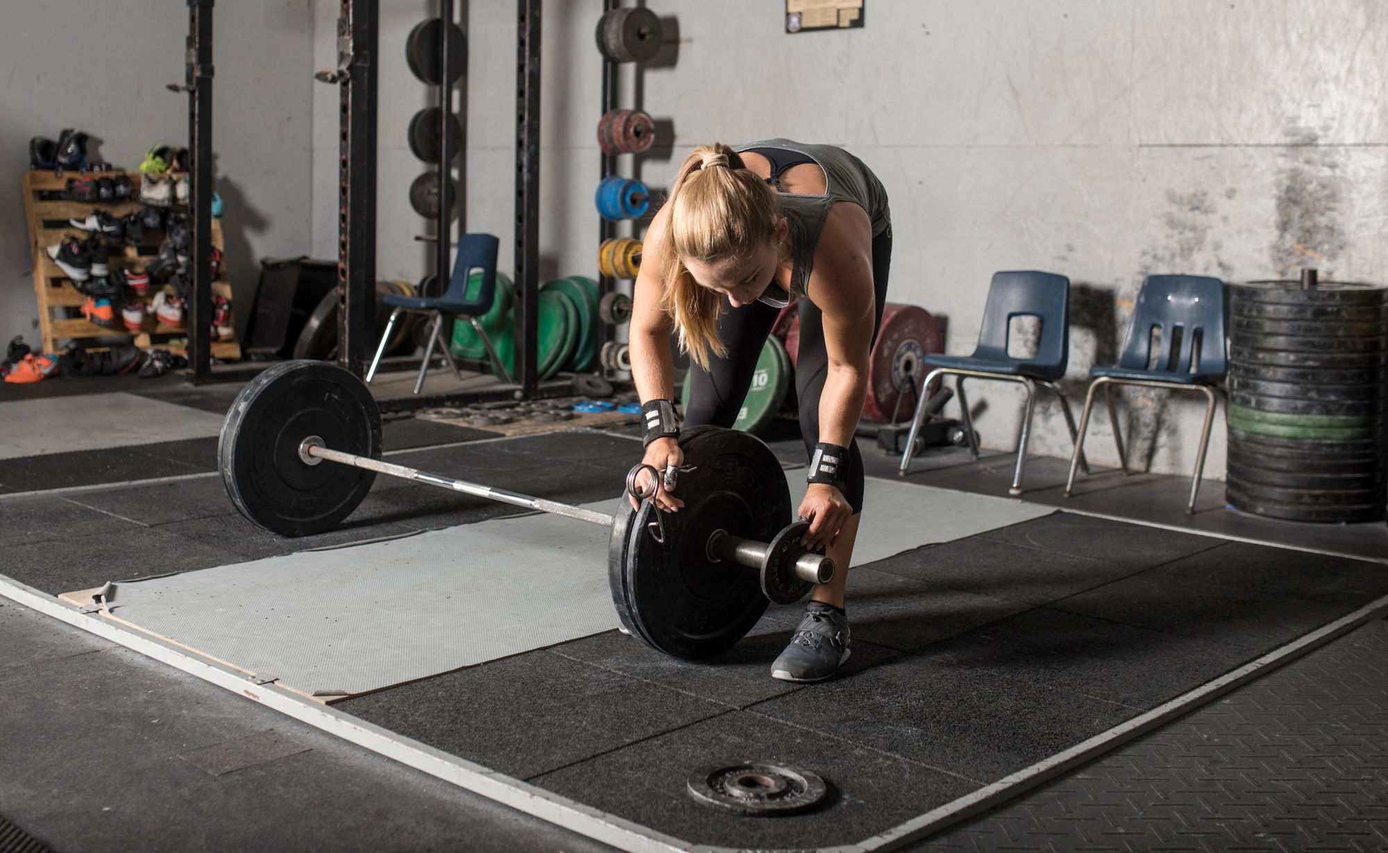 Female weight lifter loading weights onto barbell