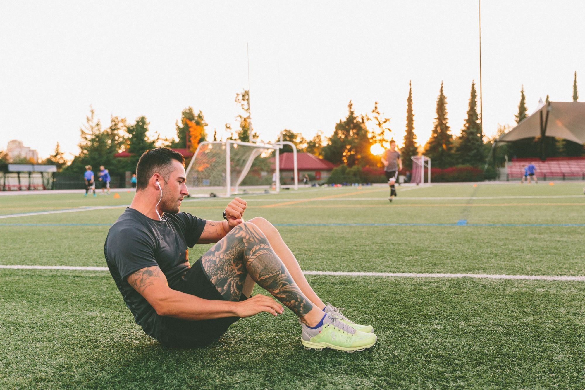 young tattooed man, checking his glucose monitor while exercising.