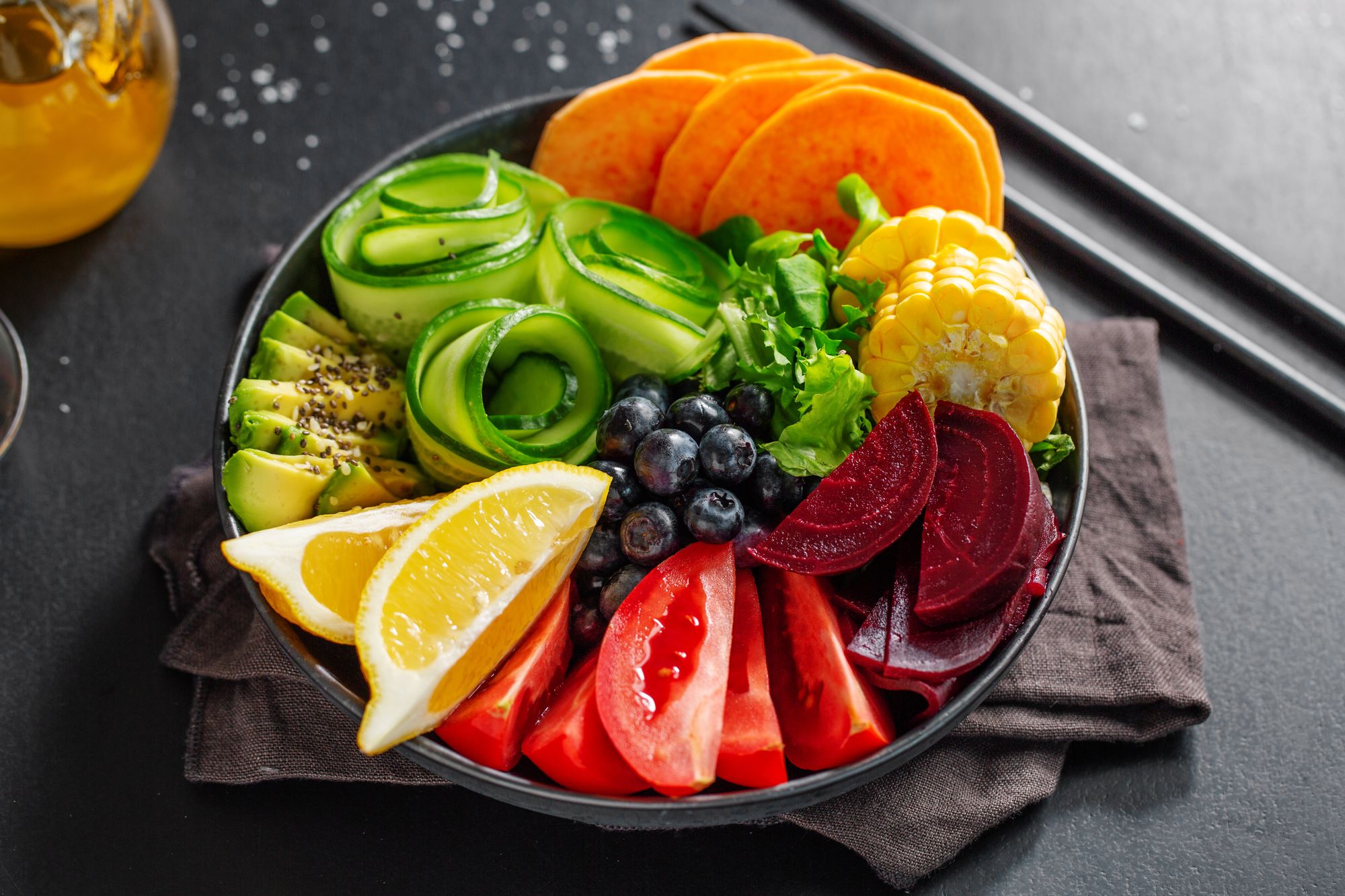 Vegan buddha bowl with vegetables and fruits served in bowl on grey background. Closeup