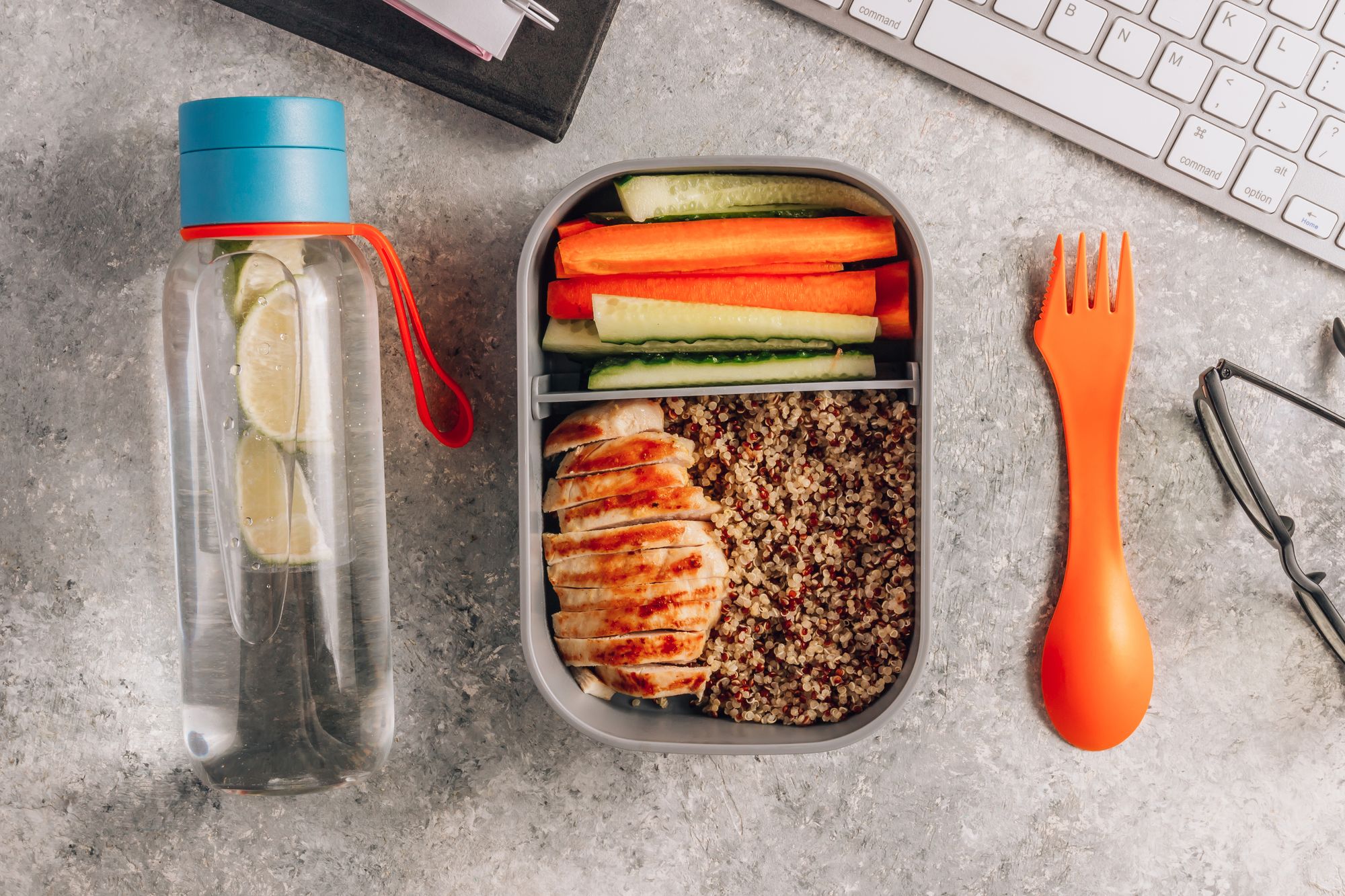 healthy meal prep containers with quinoa, chicken and vegetables plus a bottle of water