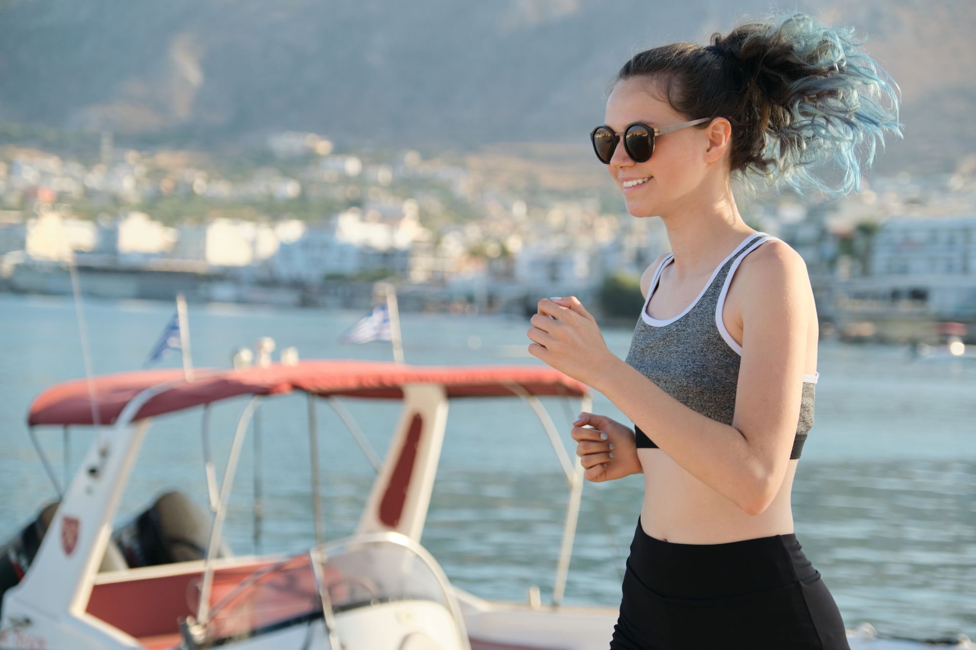 Teen girl exercising outdoor, jogging running at seaside promenade, sunny summer day