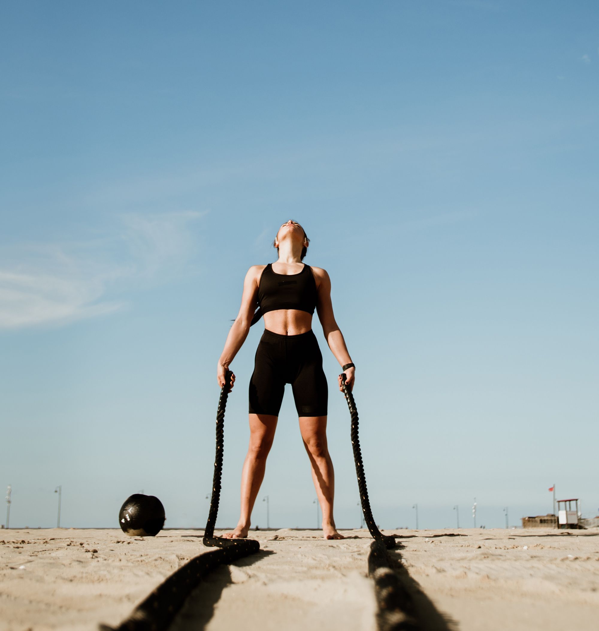 Fit and toned sportswoman working out in functional training gym at the beach