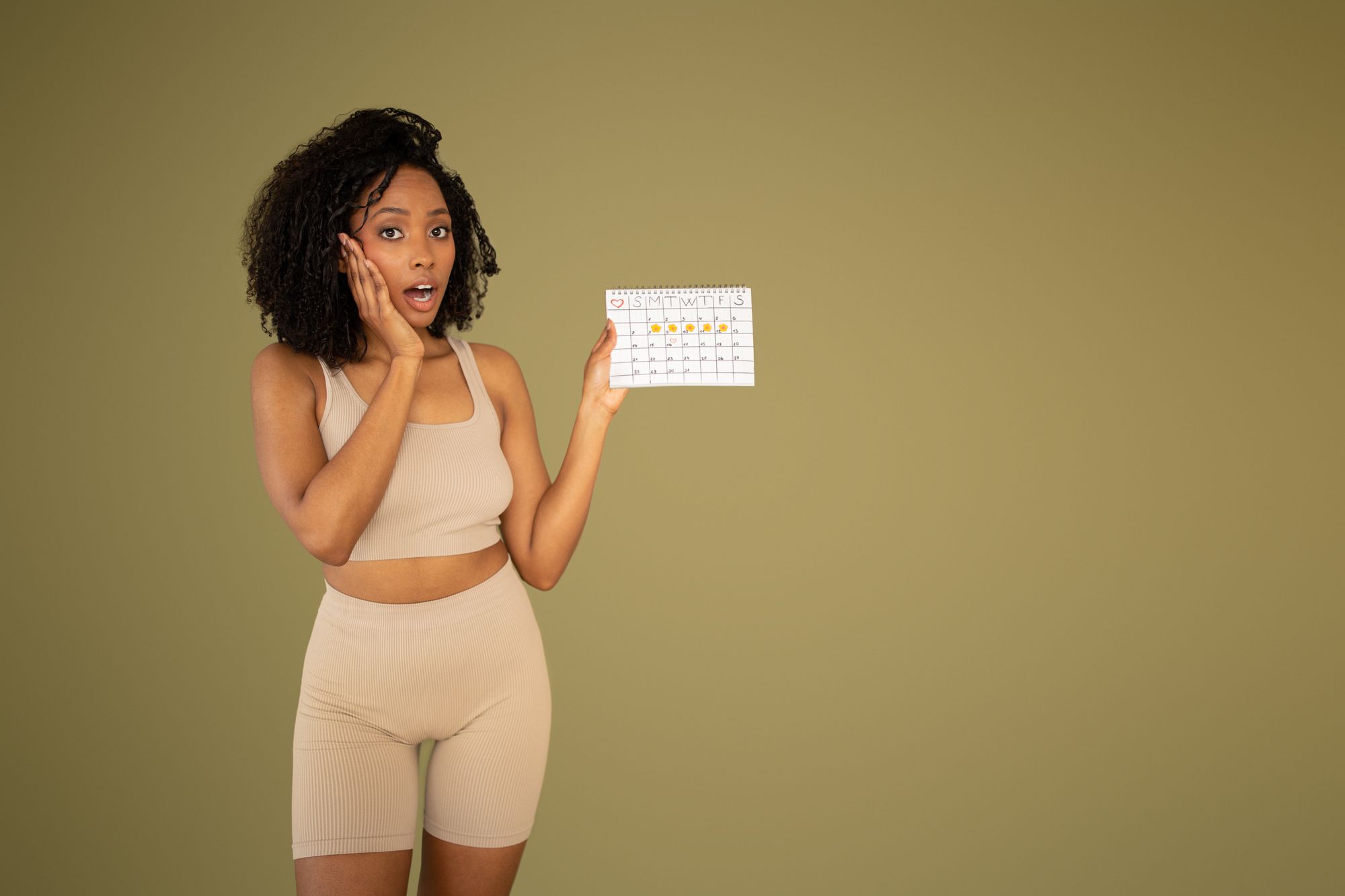 African american woman in sportswear show calendar isolated on beige studio background. Weight loss, workout, gym streak