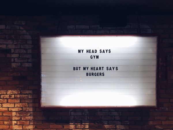 My head says gym, but my heart says burgers. A white glowing sign on a brick wall