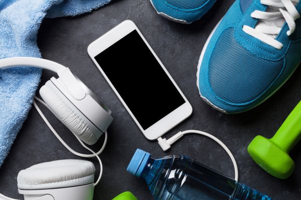Fitness concept background with sneakers, headphones, smartphone, water bottle and towel. Top view with space for your text